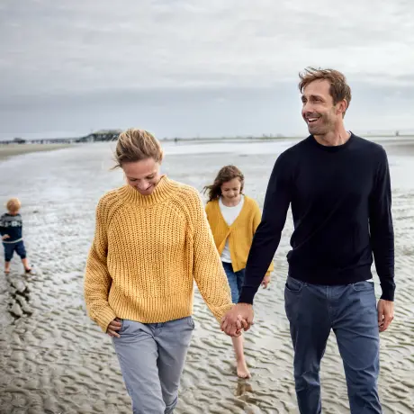Familie mit zwei Kindern geht am Strand spazieren