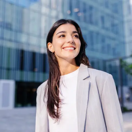 Eine Frau steht lächelnd vor einem Bürogebäude